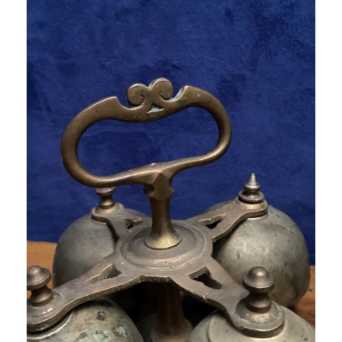 131 - AN ANTIQUE SACRISTY BELL, brass with handle, four bells, three with clappers, on circular base. Dime... 