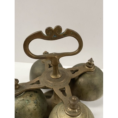 131 - AN ANTIQUE SACRISTY BELL, brass with handle, four bells, three with clappers, on circular base. Dime... 