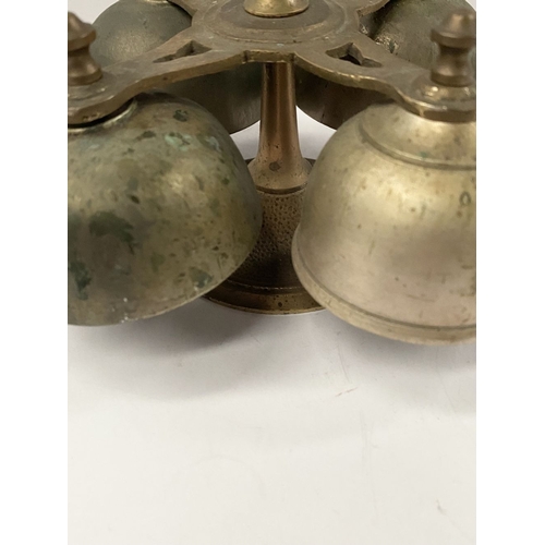 131 - AN ANTIQUE SACRISTY BELL, brass with handle, four bells, three with clappers, on circular base. Dime... 