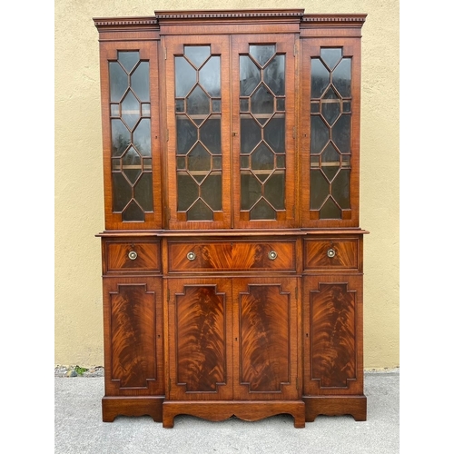 136 - A NEAT SIZED MAHOGANY BREAKFRONT BOOKCASE, with dentil cornice above four astral glazed doors reveal... 