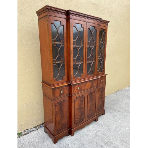 136 - A NEAT SIZED MAHOGANY BREAKFRONT BOOKCASE, with dentil cornice above four astral glazed doors reveal... 