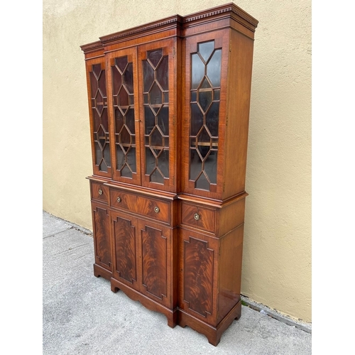 136 - A NEAT SIZED MAHOGANY BREAKFRONT BOOKCASE, with dentil cornice above four astral glazed doors reveal... 