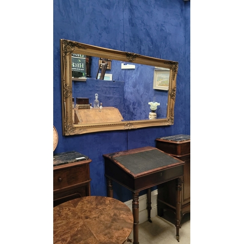 189 - A GOOD QUALITY GILT WALL MIRROR, with raised relief decoration to the frame, and a good bevelled gla... 