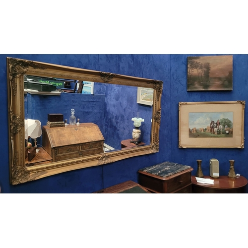 189 - A GOOD QUALITY GILT WALL MIRROR, with raised relief decoration to the frame, and a good bevelled gla... 