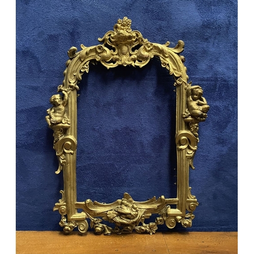 64 - A 19TH CENTURY ORNATE GILT BRONZE FRAME, neo classical with cherub mounts to sides, scrolling crest ... 