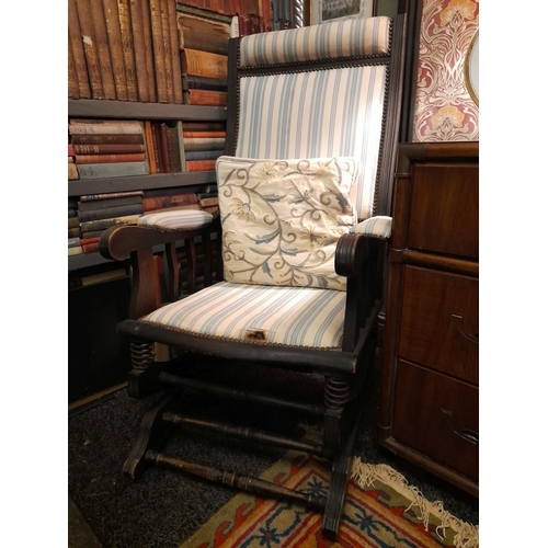 77 - AN EDWARDIAN ROCKING CHAIR, stud upholstered to headrest, backrest, armrests and seat. The supports ... 