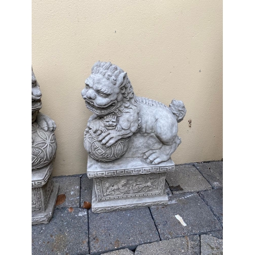 282 - A PAIR OF GARDEN ORNAMENTS IN THE FORM OF GUARDIAN LIONS / FOO DOGS, each lion standing upon a platf... 