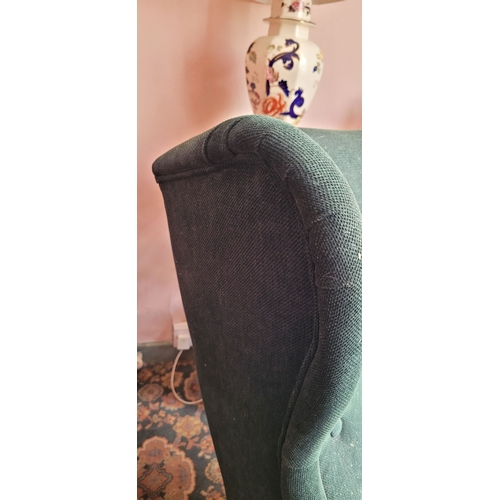 103 - A VERY GOOD CONTEMPORARY WING BACKED ARMCHAIR, in a green upholstery with button detail to the back,... 