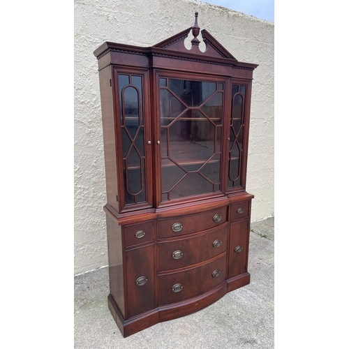 12 - A NEAT SIZED MAHOGANY BOW FRONTED BOOKCASE, with carved pediment to top above three architectural gl... 