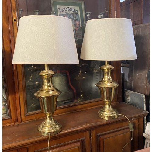 190 - A PAIR OF BRASS TABLE LAMPS, with turned supports on circular platform bases, complete with cream la... 