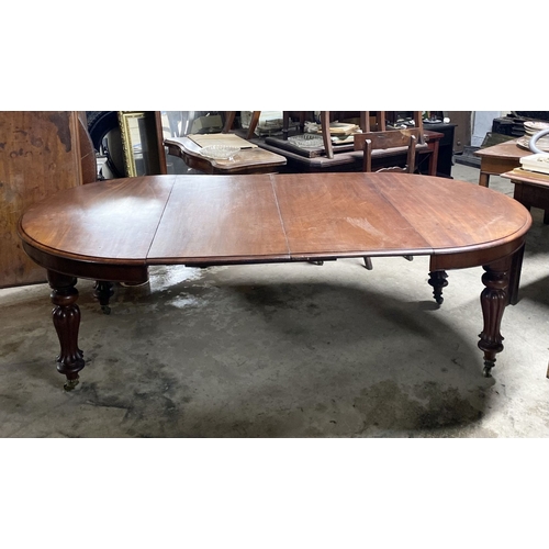 221 - A FINE MAHOGANY D-END EXTENDING DINING TABLE, raised on turned fluted leg on brass castors. Dimensio... 