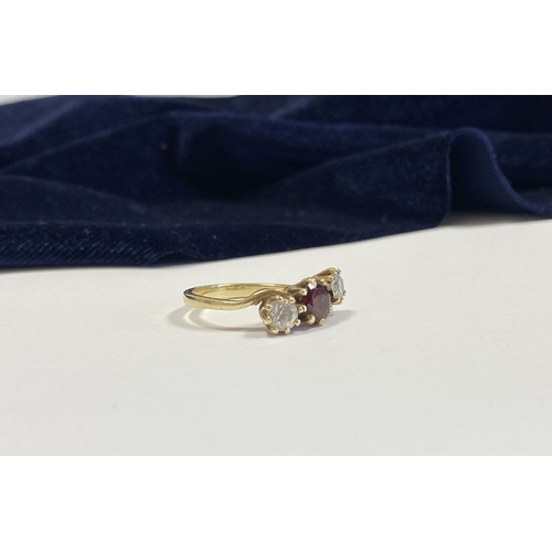 320 - A 9CT YELLOW GOLD GARNET THREE STONE RING, with round cut central garnet in raised claw setting, fla... 