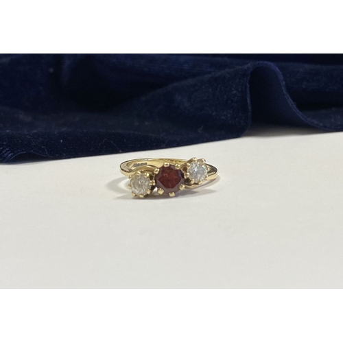 320 - A 9CT YELLOW GOLD GARNET THREE STONE RING, with round cut central garnet in raised claw setting, fla... 