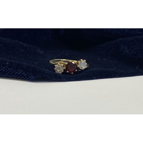 320 - A 9CT YELLOW GOLD GARNET THREE STONE RING, with round cut central garnet in raised claw setting, fla... 