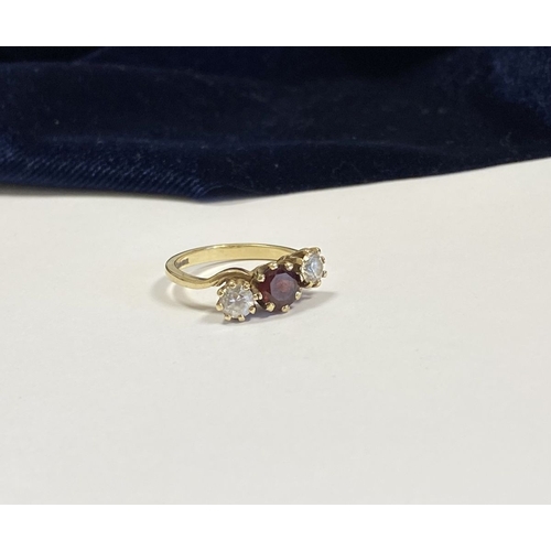 320 - A 9CT YELLOW GOLD GARNET THREE STONE RING, with round cut central garnet in raised claw setting, fla... 