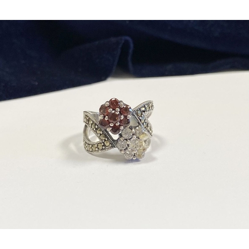 322 - A PRETTY STERLING SILVER GARNET FLORAL CROSSOVER RING, with seven round cut garnets set in floral se... 