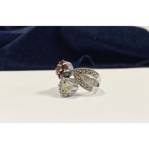 322 - A PRETTY STERLING SILVER GARNET FLORAL CROSSOVER RING, with seven round cut garnets set in floral se... 