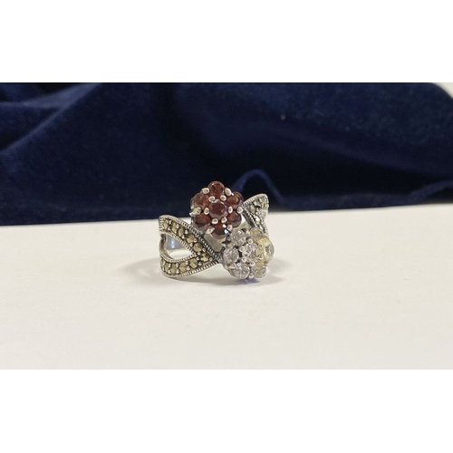 322 - A PRETTY STERLING SILVER GARNET FLORAL CROSSOVER RING, with seven round cut garnets set in floral se... 