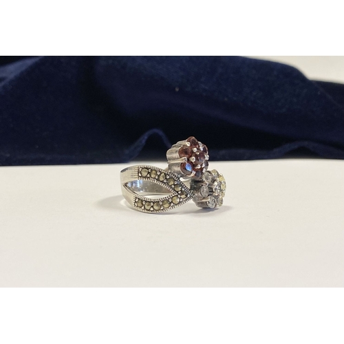 322 - A PRETTY STERLING SILVER GARNET FLORAL CROSSOVER RING, with seven round cut garnets set in floral se... 