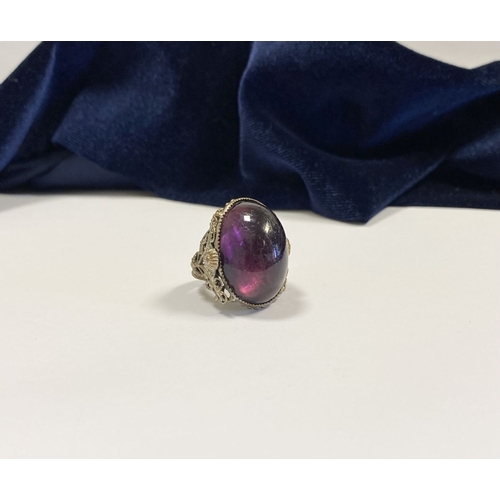 323 - A BEAUTIFUL LARGE OVAL CABOCHON CUT POLISHED CENTRE STONE RING, mounted in highly decorative silver ... 