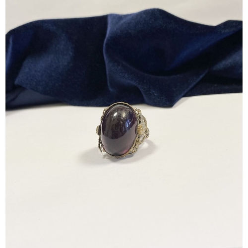 323 - A BEAUTIFUL LARGE OVAL CABOCHON CUT POLISHED CENTRE STONE RING, mounted in highly decorative silver ... 