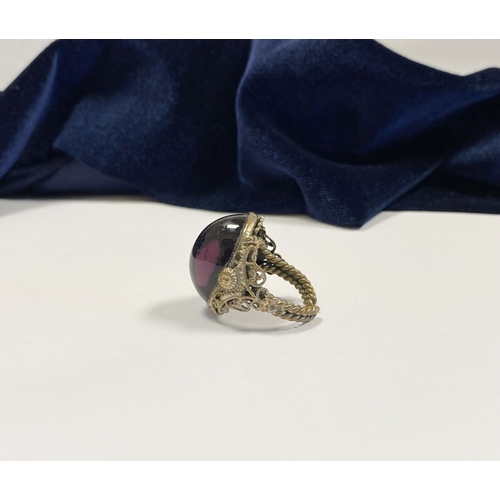 323 - A BEAUTIFUL LARGE OVAL CABOCHON CUT POLISHED CENTRE STONE RING, mounted in highly decorative silver ... 