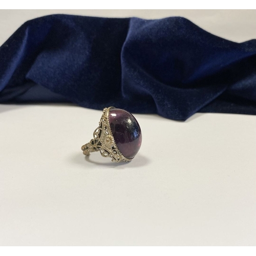 323 - A BEAUTIFUL LARGE OVAL CABOCHON CUT POLISHED CENTRE STONE RING, mounted in highly decorative silver ... 