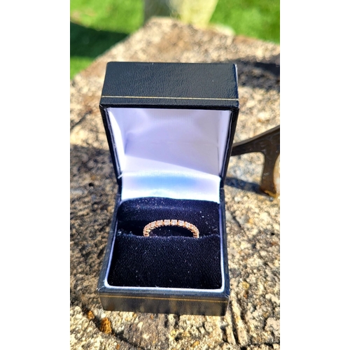 341 - A PRETTY SPARKLING ROSE GOLD DIAMOND ETERNITY RING, with round brilliant cut diamonds running along ... 