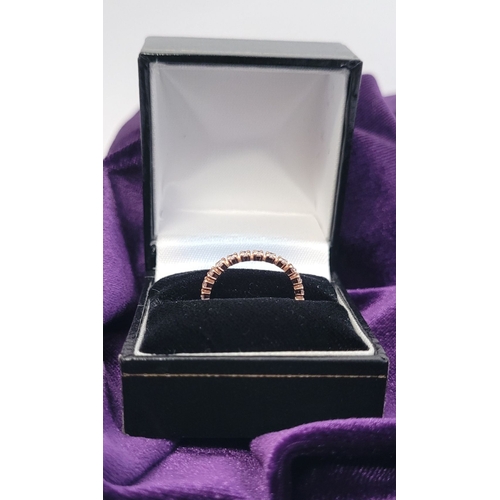 341 - A PRETTY SPARKLING ROSE GOLD DIAMOND ETERNITY RING, with round brilliant cut diamonds running along ... 