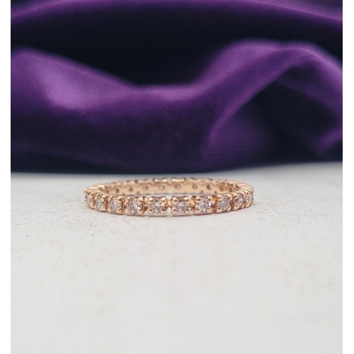 341 - A PRETTY SPARKLING ROSE GOLD DIAMOND ETERNITY RING, with round brilliant cut diamonds running along ... 