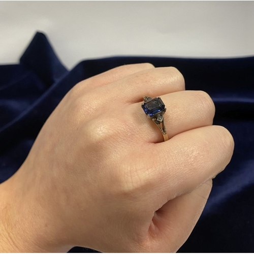 80 - A PRETTY 9CT GOLD PLATED SAPPHIRE RING, large emerald cut sapphire in claw setting, flanked by marca... 