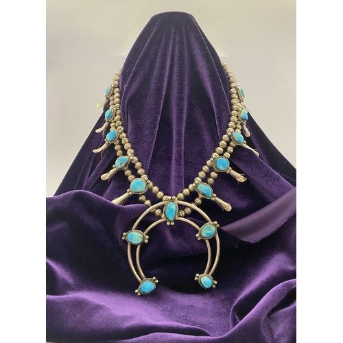 215 - A VINTAGE NAVAJO STERLING SILVER TURQUOISE SQUASH BLOSSOM NECKLACE, with two rows of beads to neckla... 