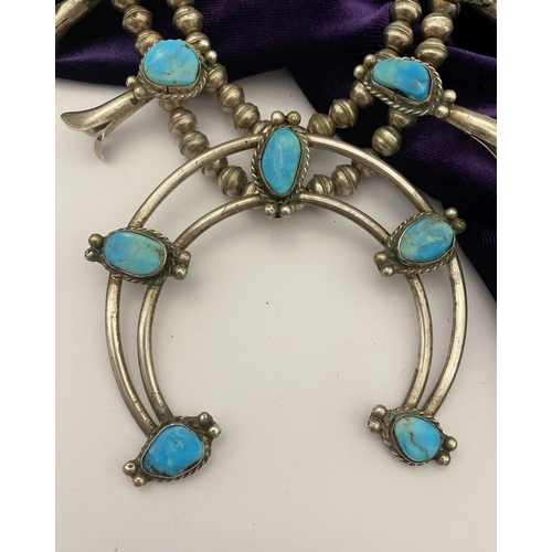 215 - A VINTAGE NAVAJO STERLING SILVER TURQUOISE SQUASH BLOSSOM NECKLACE, with two rows of beads to neckla... 