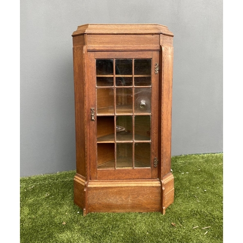 229 - AN ANTIQUE OAK CORNER DISPLAY CABINET, with glazed door revealing shelved interior above shaped base... 