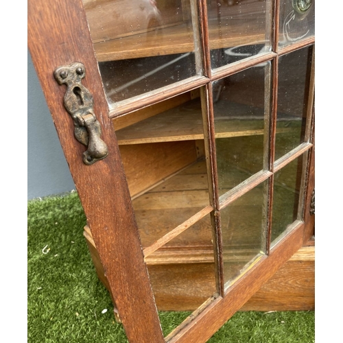229 - AN ANTIQUE OAK CORNER DISPLAY CABINET, with glazed door revealing shelved interior above shaped base... 