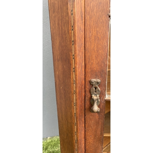 229 - AN ANTIQUE OAK CORNER DISPLAY CABINET, with glazed door revealing shelved interior above shaped base... 