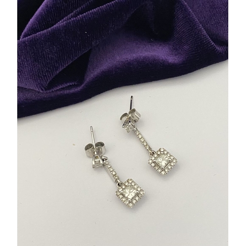 13 - AN ELEGANT PAIR OF 14CT WHITE GOLD DIAMOND DROP EARRINGS, each featuring princess cut diamonds above... 