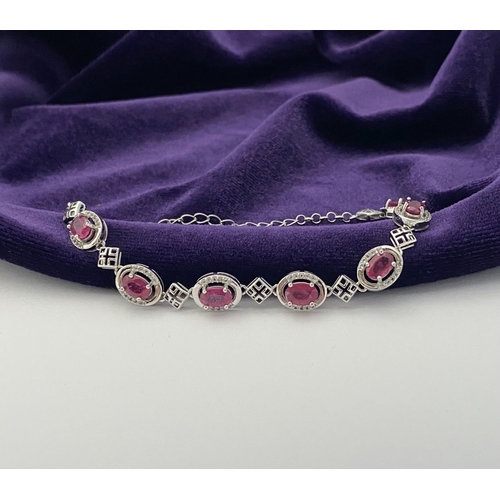 18 - AN ELEGANT 18CT GOLD PLATED RUBY BRACELET, featuring seven oval cut rubies, clarity enhanced for exc... 