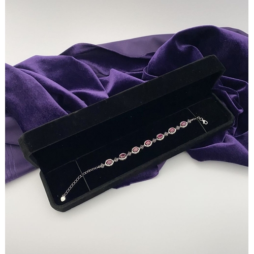 18 - AN ELEGANT 18CT GOLD PLATED RUBY BRACELET, featuring seven oval cut rubies, clarity enhanced for exc... 