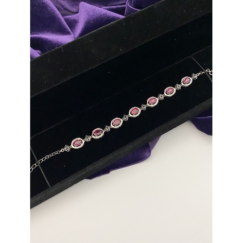 18 - AN ELEGANT 18CT GOLD PLATED RUBY BRACELET, featuring seven oval cut rubies, clarity enhanced for exc... 