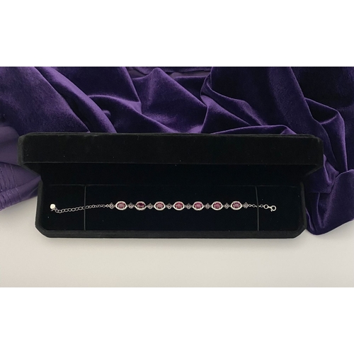 18 - AN ELEGANT 18CT GOLD PLATED RUBY BRACELET, featuring seven oval cut rubies, clarity enhanced for exc... 