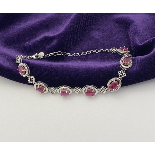 18 - AN ELEGANT 18CT GOLD PLATED RUBY BRACELET, featuring seven oval cut rubies, clarity enhanced for exc... 