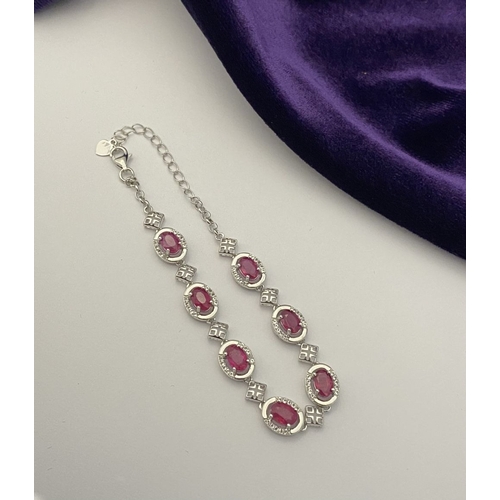 18 - AN ELEGANT 18CT GOLD PLATED RUBY BRACELET, featuring seven oval cut rubies, clarity enhanced for exc... 