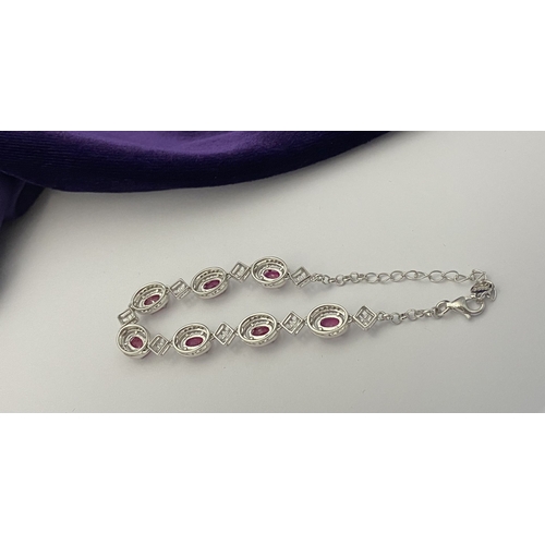 18 - AN ELEGANT 18CT GOLD PLATED RUBY BRACELET, featuring seven oval cut rubies, clarity enhanced for exc... 