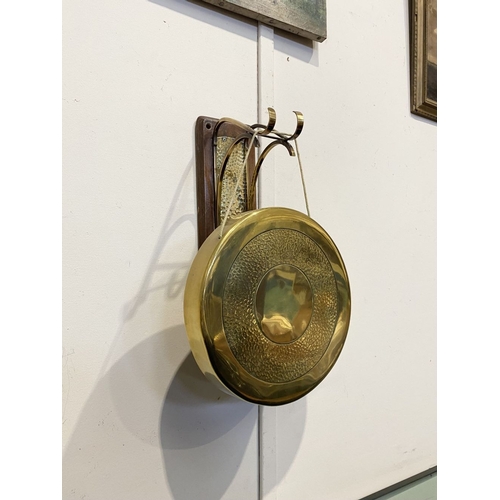 46 - A BRASS WALL HANGING DINNER GONG, wall mountable hardwood stand, with brass hanging hooks and hammer... 