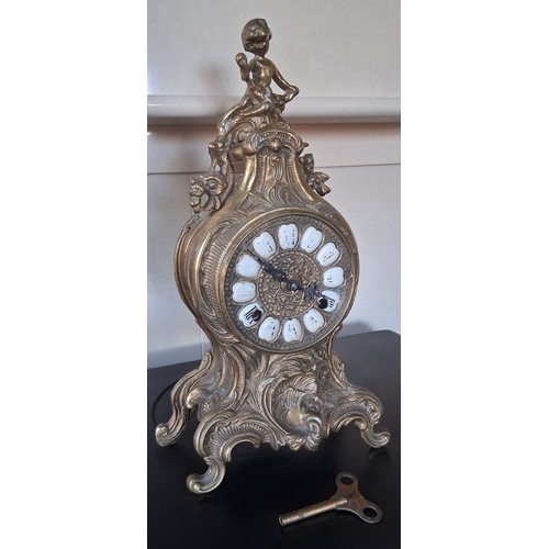 55 - A LOUIS XV STYLE BRASS FRANZ HERMLE MANTLE CLOCK, intricate piece with figural putti finial, raised ... 