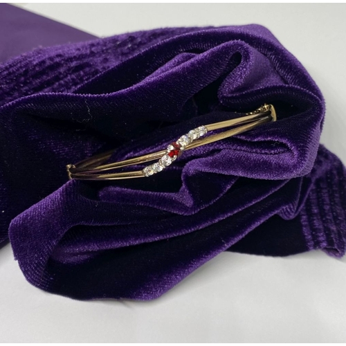 60 - A BEAUTIFUL GOLD GARNET BRACELET, with central round cut vibrant garnet flanked by six round cut cle... 