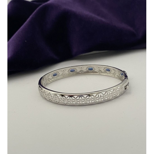 82 - AN 18CT WHITE GOLD-PLATED SAPPHIRE BANGLE BRACELET, featuring five oval cut sapphires, claw set, sur... 