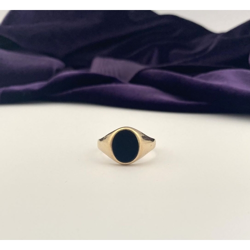 83 - AN IRISH 9CT GOLD GENTLEMAN'S ONYX SIGNET RING, featuring oval onyx in bezel setting, with tapered s... 