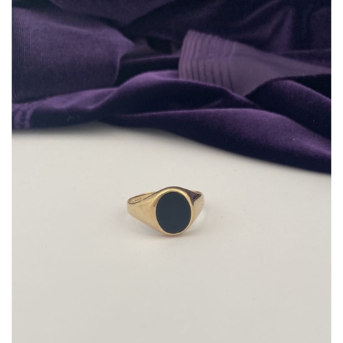 83 - AN IRISH 9CT GOLD GENTLEMAN'S ONYX SIGNET RING, featuring oval onyx in bezel setting, with tapered s... 